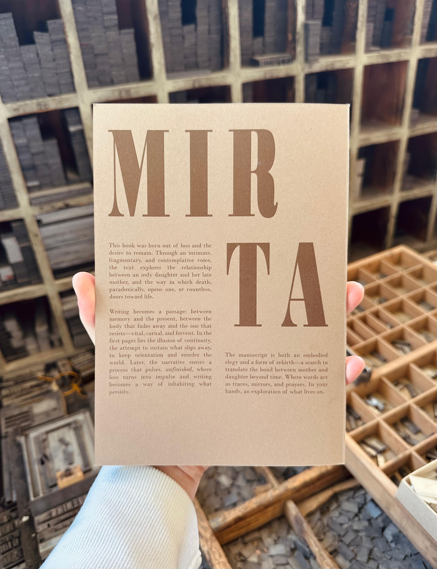 The back cover of In the name of Mirta held inside a letterpress workshop