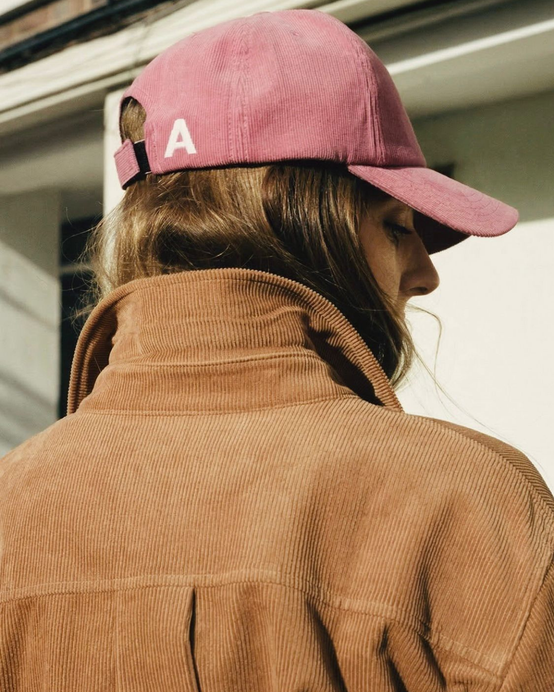 Agostina Avaro photographed from behind in a corduroy jacket and pink cap